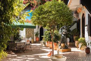 a courtyard with a tree and a table and chairs at Lalla Soulika in Tangier