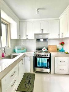a white kitchen with a stove and a sink at Camella Home Greta Model Rental in Bacolod in Bacolod