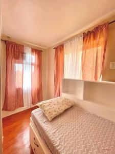 a bedroom with a bed and two windows at Camella Home Greta Model Rental in Bacolod in Bacolod