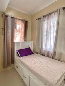a bedroom with a bed with a purple pillow on it at Camella Home Greta Model Rental in Bacolod in Bacolod