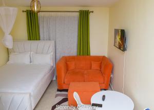 een woonkamer met een oranje stoel en een bank bij Serenity Getaway STUDIO apartment near JKIA & SGR with KING BED, WIFI, NETFLIX and SECURE PARKING in Syokimau