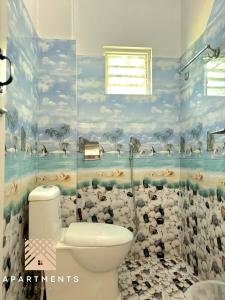 a bathroom with a toilet and a mural of the ocean at Nishan Apartments -Lakeside in Pokhara