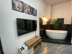a bathroom with a tub and a tv on the wall at Hotel Hostal Caps Cartagena in Cartagena de Indias