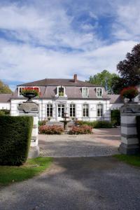 duży biały dom z budkami kwiatowymi na podjeździe w obiekcie Les Hys de Verdenne w mieście Marche-en-Famenne