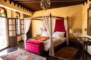 - une chambre avec un lit à baldaquin et une tête de lit rouge dans l'établissement Lalla Soulika, à Tanger