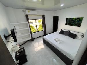 1 dormitorio con cama blanca y ventana en Hotel SG, en Doradal