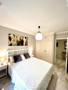 sypialnia z białym łóżkiem i lampką w obiekcie PUERTO DELUXE w Maladze