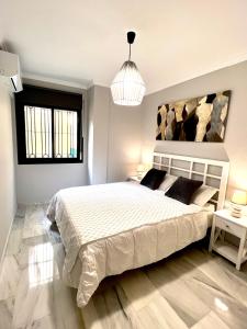 sypialnia z dużym białym łóżkiem i oknem w obiekcie PUERTO DELUXE w Maladze