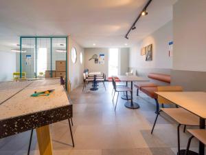 a waiting room with tables and a ping pong table at ibis budget Forbach Centre in Forbach