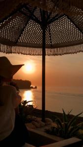 a sunset over the ocean with a straw umbrella at Ulunia in Uluwatu