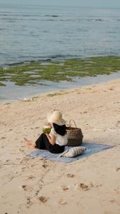 a person sitting on a towel on the beach at Ulunia in Uluwatu