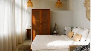 a bedroom with a white bed and a wooden cabinet at Ulunia in Uluwatu