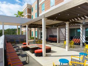 a patio with colorful chairs and tables and a building at Home2 Suites by Hilton Orlando South Davenport in Davenport