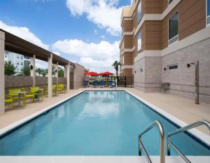 una piscina en un hotel con mesas y sillas en Home2 Suites by Hilton Orlando South Davenport, en Davenport