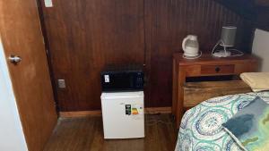 a room with a small refrigerator next to a bed at BELLAS Y COMODAS HABITACIONES EN LA SERENA in La Serena