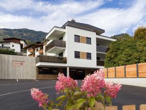 um edifício branco com flores cor-de-rosa num parque de estacionamento em Apart Klocker em Fügen
