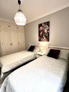 sypialnia z 2 łóżkami i obrazem na ścianie w obiekcie PUERTO DELUXE w Maladze