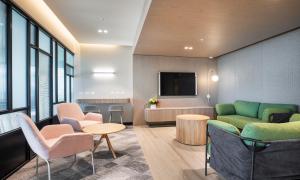 a waiting room with chairs and tables and a tv at Holiday Inn & Suites Geelong, an IHG Hotel in Geelong