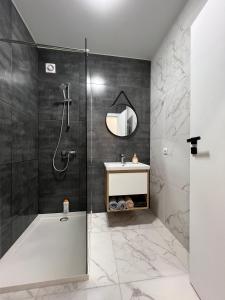 ein Bad mit einer Dusche, einem Waschbecken und einem Spiegel in der Unterkunft Smart Modern loft apartments in Iwano-Frankiwsk