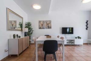 una sala da pranzo con tavolo, sedie e TV di Residencial Las Candelarias 30 ad Agaete