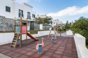 a playground with two swings and a slide at Residencial Las Candelarias 30 in Agaete