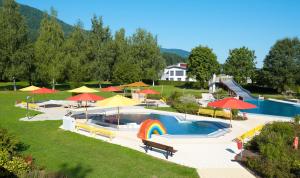 a swimming pool with umbrellas and a resort at Landhaus Fürberger in Anger