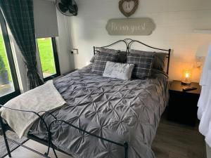 um quarto com uma cama com um edredão cinzento e almofadas em Dolafon farm luxury glamping cabin with hot tub em St Asaph