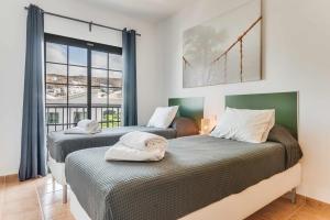 2 camas en una habitación con ventana en Residencial Las Candelarias 35, en Agaete