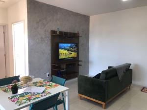a living room with a table and a television at Apt- Suíte - Quadra mar - Aeroporto/Beto Carreiro in Navegantes
