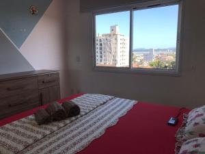 a bedroom with a bed with a large window at Apt- Suíte - Quadra mar - Aeroporto/Beto Carreiro in Navegantes