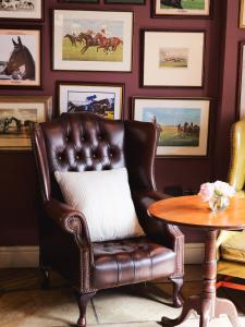 una silla de cuero marrón sentada en una habitación con una mesa en The Bildeston Crown en Bildeston