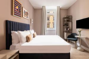 1 dormitorio con 1 cama blanca grande y TV en numa I Linea en Roma