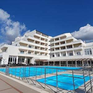 a large building with a swimming pool in front of it at AFYTOS ÖREN BEACH PRESTİJ in Burhaniye