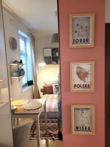 a room with a pink wall with a table and a bed at Przytulne gniazdko blisko Wisły in Toruń