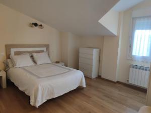 a white bedroom with a bed and a window at Chalet con amplio jardín in Casalarreina