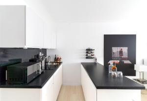 a kitchen with white cabinets and a black counter top at Beyond Living x American Psycho in Gelsenkirchen