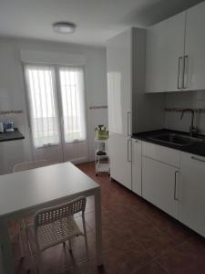 a kitchen with white cabinets and a table and chairs at Chalet con amplio jardín in Casalarreina