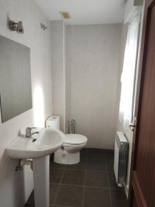 a white bathroom with a toilet and a sink at Chalet con amplio jardín in Casalarreina +3 photos
