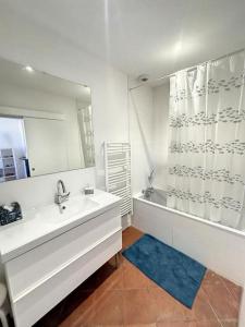 ein Badezimmer mit einem Waschbecken, einer Badewanne und einem Spiegel in der Unterkunft L'écrin Lauragais - Grande maison, 3 chambres 3sdb in Villefranche-de-Lauragais
