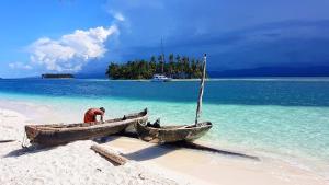 un hombre de pie en un barco en una playa en El Más Grande Catamarán de San Blas - TODO INCLUIDO - en Isla Wichitupo Grande