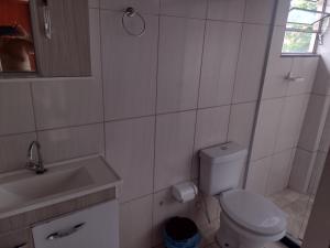 a white bathroom with a toilet and a sink at Pousada Mar e Sol in Saquarema
