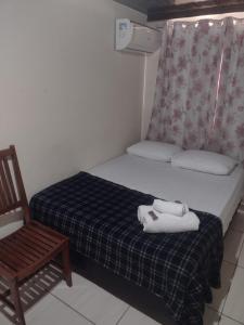 a small bedroom with a bed and a chair at Pousada Mar e Sol in Saquarema