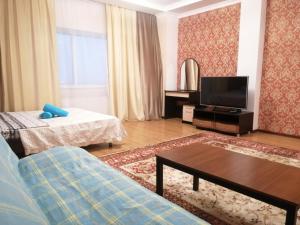 een woonkamer met een bank en een tv bij Северное Сияние 41 этаж 01 in Astana
