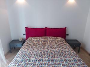 ein Schlafzimmer mit einem Bett mit roten Kissen und 2 Tischen in der Unterkunft Il Melograno in Toscana in Castelfranco di Sopra