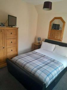 1 dormitorio con 1 cama, vestidor y TV en The Grapes Hotel en Newcastleton