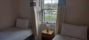 two twin beds in a room with a window at The Grapes Hotel in Newcastleton