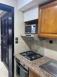 a kitchen with a stove and a microwave at Appartement De Luxe Marina Agadir in Agadir