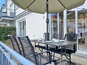 a table with chairs and an umbrella on a patio at Am Stadtwald in Kühlungsborn