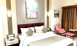 a hotel room with a bed and a pink chair at PUSHPAK HOTEL & CONVENTION in Bhubaneshwar