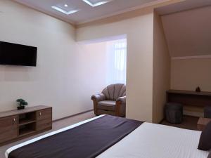 a bedroom with a bed and a chair and a television at Hotel & Banquet Hall SV Airport Parkway in Todoreshty